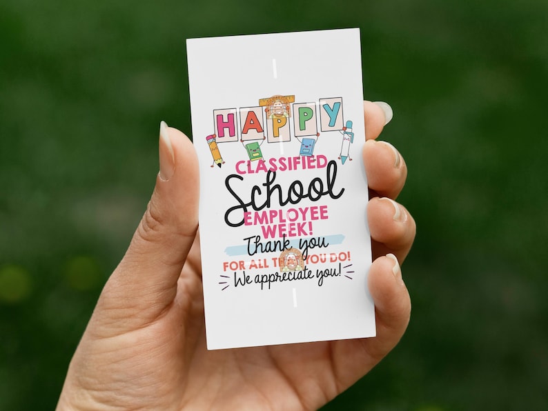 May include: A white card held in a hand with the text "HAPPY CLASSIFIED School EMPLOYEE WEEK! Thank you FOR ALL THAT YOU DO! We appreciate you!" in various colors and fonts. The card has a green background.