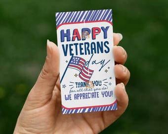 May include: A rectangular card with a red, white, and blue design, held in a hand. The card reads "HAPPY VETERANS day" with an American flag graphic. Below the flag, it says "THANK YOU for all that you do! WE APPRECIATE YOU!"