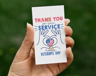May include: A white card with the text "THANK YOU for your SERVICE" in red and blue. The card features a heart made of hands with an American flag design and the words "happy VETERANS DAY".