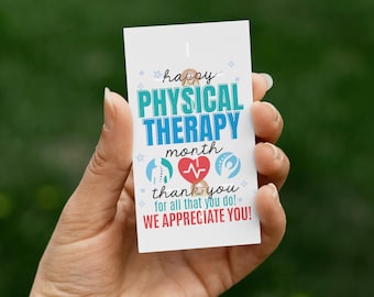 May include: A white card with the text "happy PHYSICAL THERAPY month thank you for all that you do! WE APPRECIATE YOU!" in blue, teal, and red. The card is held in a hand against a blurred green background.