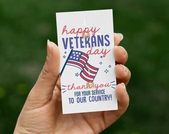 May include: A white card held in a hand, with the text "Happy Veterans Day" in red and blue script. An American flag graphic is featured, along with the words "thank you for your service to our country!"
