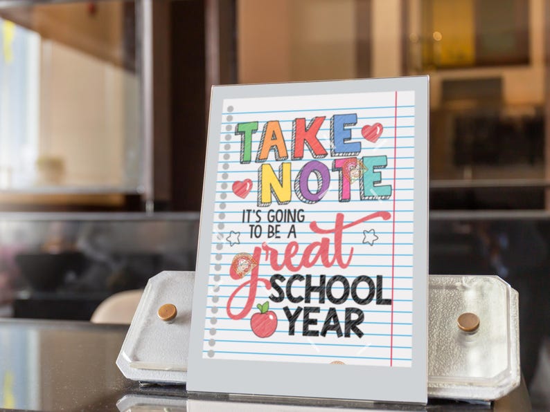 May include: A white sign with a colourful "Take Note" message and a red apple graphic. The sign says "It's going to be a great school year".
