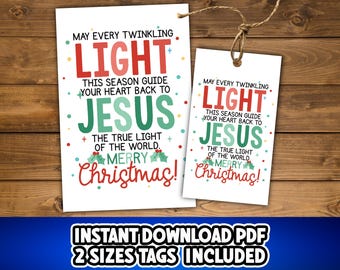 May include: Two white Christmas gift tags with the text "May every twinkling light...Merry Christmas!" in red, green, and white. The tags are on a wooden background and are tied with twine. The bottom of the image has the text "INSTANT DOWNLOAD PDF 2 SIZES TAGS INCLUDED".