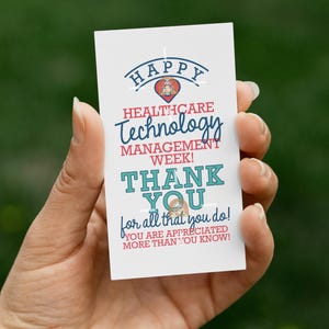 May include: A white card with the text "HAPPY HEALTHCARE TECHNOLOGY MANAGEMENT WEEK! THANK YOU for all that you do! YOU ARE APPRECIATED MORE THAN YOU KNOW!" is held in a hand.