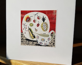 May include: A white plate with a pineapple, cherries, and other fruit on a red and black background. A white teacup with blue and yellow flowers is next to the plate.