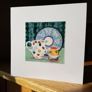 May include: A white teacup with red, green and yellow polka dots, a small yellow can with the text "1/2 NET CONTENTS", and a blue and white patterned plate with a green background.