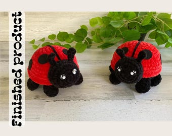 May include: Two crocheted ladybug toys with black spots and white eyes. The ladybugs are sitting on a wooden surface.