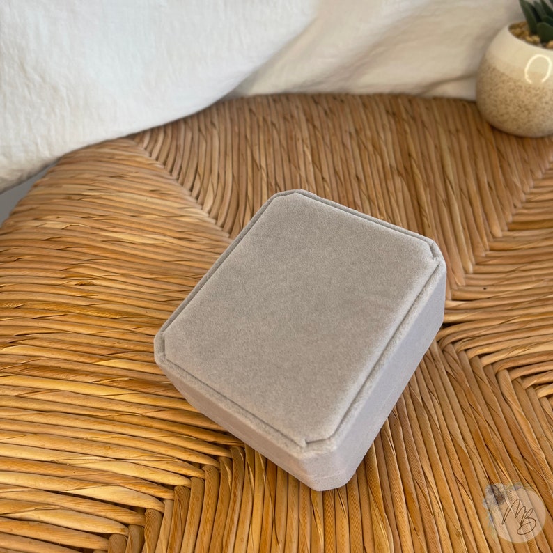 Peut inclure: Une bo&icirc;te &agrave; bijoux en velours gris de forme carr&eacute;e avec un bord l&eacute;g&egrave;rement sur&eacute;lev&eacute;.