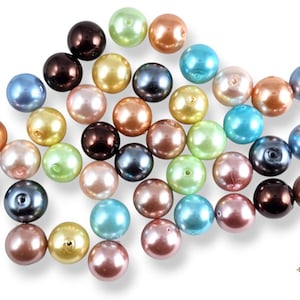 Pode incluir: Uma coleção de 30 contas com aparência de pérola em várias cores pastel, incluindo azul claro, rosa, verde e marrom. As contas são lisas e brilhantes, com um leve brilho iridescente.