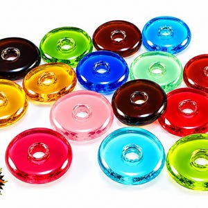 May include: A collection of circular, translucent glass beads in various colours including red, blue, green, yellow, pink, and brown. Each bead features a central hole. The logo LUZ ITALY is printed in the bottom left corner with a sun graphic.