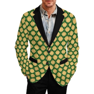 May include: A green blazer with a repeating gold floral pattern. The blazer has a black lapel and black pocket trim. The buttons are black. The person is wearing a denim shirt and black pants.