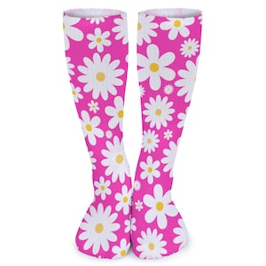 Peut inclure: Paire de chaussettes hautes aux genoux avec un fond rose vif et un motif répété de marguerites blanches à centres jaunes. Les chaussettes sont conçues pour être portées sur les jambes.