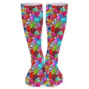 Puede incluir: Un par de calcetines hasta la rodilla con un patrón vibrante y colorido. El diseño presenta un patrón repetido de corazones, fresas, arcoíris, barras de chocolate y otros elementos caprichosos. Los calcetines tienen un puño blanco y una estética lúdica y llamativa. Aproximadamente 40 cm de largo.
