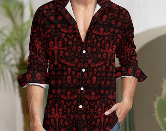 May include: A button-down shirt with a black background and a repeating pattern of red skulls, crosses, bats, and roses. The shirt has a white collar and cuffs. The sleeves are rolled up, and the shirt is unbuttoned at the top.