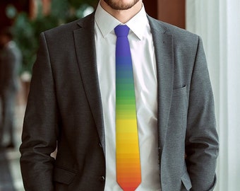 May include: A man wearing a dark gray suit jacket and a white dress shirt with a rainbow tie. The tie has a gradient of colors from purple to yellow.