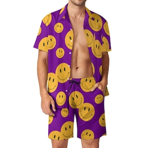 May include: A purple short-sleeved button-up shirt and matching shorts with a yellow smiley face pattern.