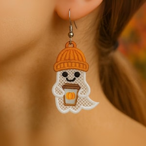 Puede incluir: Pendientes bordados de fantasma sonriente, con gorro naranja y taza de caf&eacute; con calabaza. El fantasma blanco tiene un dise&ntilde;o de encaje. Los pendientes tienen ganchos plateados.