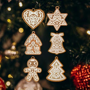 Può includere: Sei decorazioni natalizie in stile pan di zenzero con dettagli in glassa bianca. Gli ornamenti includono un cuore, una stella, una casa, una campana, un omino di pan di zenzero e un albero di Natale. Sfondo verde sfocato con luci.