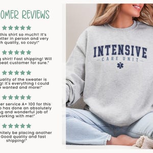 May include: A gray sweatshirt with the text "INTENSIVE CARE UNIT" in navy blue lettering and a blue star of life symbol. The sweatshirt is being modeled by a person wearing light blue jeans.