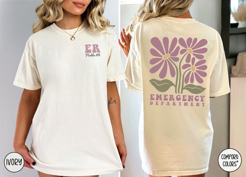 May include: Two ivory t-shirts with different designs. The front of the first shirt has the letters "ER" and the text "Middle RN". The back of the second shirt has a design of three purple flowers with green leaves and the text "Emergency Department".