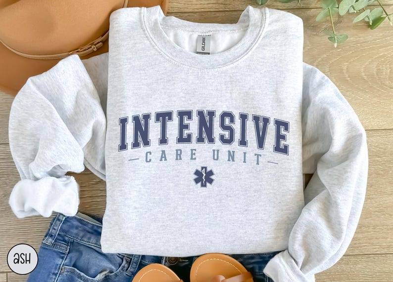 May include: A gray sweatshirt with the text "INTENSIVE CARE UNIT" in blue lettering and a blue medical star symbol.