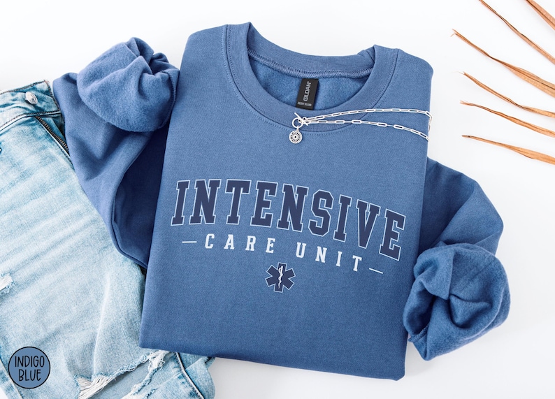 May include: A blue sweatshirt with the text "INTENSIVE CARE UNIT" in white letters with a black outline. A small medical symbol is below the text.