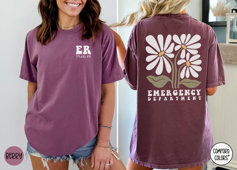 May include: A purple t-shirt with the text "ER" and "Middle TN" on the front and a design of three white daisies with green leaves and the text "EMERGENCY DEPARTMENT" on the back.