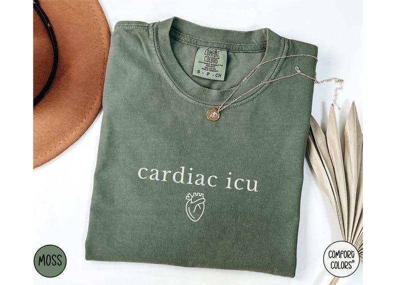 Pu&ograve; includere: Una maglietta verde con il testo "cardiac icu" e una piccola grafica a forma di cuore. La maglietta &egrave; realizzata da Comfort Colors.