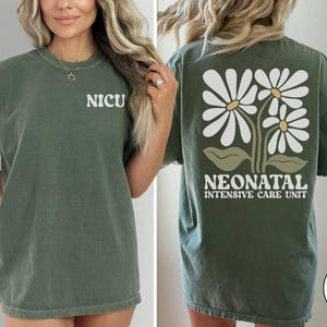 Może przedstawiać: Zielony T-shirt z napisem "NICU" z przodu i "NEONATAL INTENSIVE CARE UNIT" z kwiatowym wzorem z tyłu. Koszulka jest wygodna i luźna.