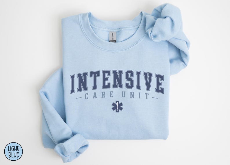 May include: Light blue sweatshirt with the text "INTENSIVE CARE UNIT" in navy blue letters with a navy blue star of life symbol.