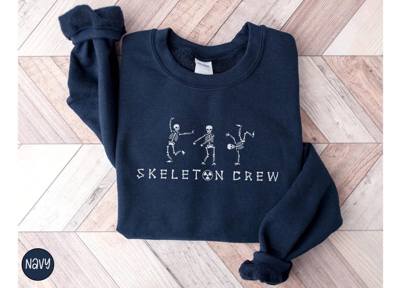 May include: Navy blue sweatshirt with a white graphic of three skeletons dancing and the text "Skeleton Crew".