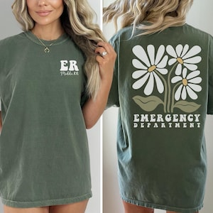May include: A green t-shirt with the text "ER" and "Middle, TN" on the front and a graphic of white daisies with green leaves and the text "Emergency Department" on the back.