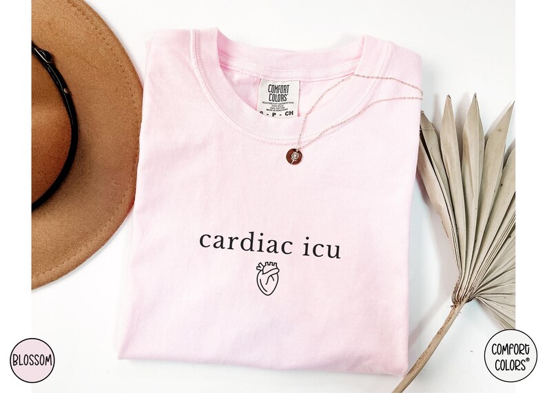 Pu&ograve; includere: Una maglietta rosa con il testo "cardiac icu" e una piccola grafica a forma di cuore. La maglietta &egrave; realizzata da Comfort Colors.