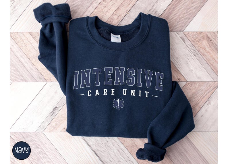 May include: Navy blue sweatshirt with the text "INTENSIVE CARE UNIT" in white lettering and a white medical star with a snake graphic.