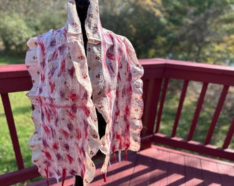 May include: A white silk scarf with a ruffled edge and a pink and red floral pattern. The scarf is draped over a mannequin.