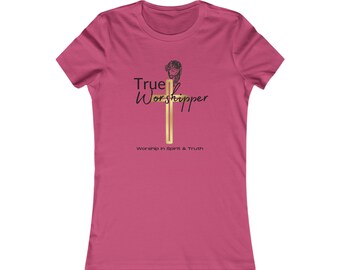May include: A dark pink short-sleeve t-shirt featuring a gold cross graphic with a black line-art illustration of a face above it. The text True Worshipper is printed in black, with the phrase Worship in Spirit & Truth below the cross.