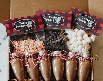 May include: A gift box filled with ingredients for making hot chocolate. The box includes chocolate mix, mini marshmallows, peppermint pieces, and chocolate chips. The box is decorated with red and black plaid paper and the words "Tasty Treats" printed on the top.