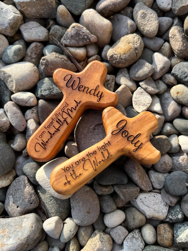 May include: Two wooden crosses with rounded edges, engraved with names and inspirational quotes. One reads "Wendy, I am fearfully and wonderfully made." The other says "Jody, You are the light of the World."