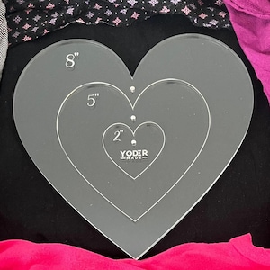 Könnte beinhalten: Ein Satz aus drei herzförmigen Acrylschablonen zum Basteln. Die Schablonen haben einen Durchmesser von 5 cm, 13 cm und 20 cm. Die Schablonen sind transparent und auf der kleinsten Schablone steht "Yoder Made".