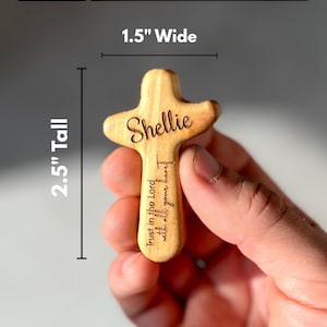 May include: A small, wooden pocket cross with the name "Shellie" engraved on it. The cross is 2.5 inches tall and 1.5 inches wide. The text "Trust in the Lord with all your heart" is also engraved on the cross. The words "Small Pocket Cross Dimensions" are at the top.