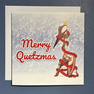 May include: A Christmas card with the text "Merry Quetzmas" in red script. The illustration features a stylized dinosaur decorated as a Christmas tree with a star on top and red garland.