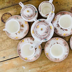 May include: A vintage tea set with a floral pattern. The set includes a teapot, creamer, sugar bowl, and four teacups and saucers.