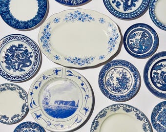 May include: A collection of blue and white ceramic plates with various designs, including floral patterns, dragons, and ships. The plates are arranged on a white background.