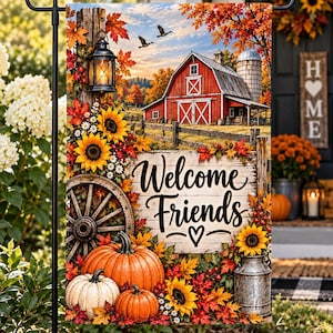 Puede incluir: Una bandera de jardín rectangular que muestra un granero rojo, un silo y un letrero de madera con el texto Welcome Friends y un corazón. La escena incluye calabazas naranjas y blancas, girasoles, hojas de otoño y una linterna de metal.