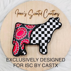 以下が含まれることがあります： 「Irene's Scented Creations」および「EXCLUSIVELY DESIGNED FOR ISC BY CASTX」という文字が刻まれた円形の木製プレート。中央には牛の形をした切り抜きがあり、後ろ半分は黒とホットピンクの花柄、前半分は黒と白の市松模様で、どちらもグリッター仕上げが施されています。