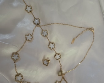 May include: A gold necklace and earrings set with white flower-shaped pendants. The necklace has a delicate chain and multiple flower pendants.