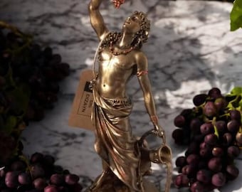 Può includere: Scultura in bronzo di una persona che tiene uva e una brocca, versando liquido. La scultura è su una base con un'etichetta che dice "DECORATIV".