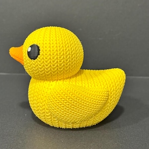 May include: A yellow rubber duck with a textured surface and black eyes. The duck is a bath toy.