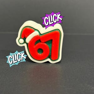 May include: A festive Christmas-themed charm featuring the number 67 in red, outlined in white and green, and topped with a Santa hat. The word "CLICK" appears in speech bubbles, suggesting an interactive element.