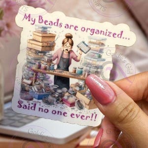 May include: A sticker with a cartoon illustration of a woman surrounded by containers of beads. The text on the sticker reads "My Beads are organized... Said no one ever!"